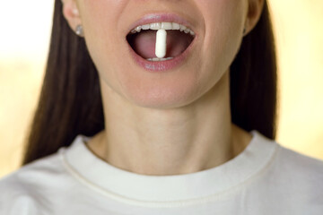 Wall Mural - Young woman holding a tablet with her teeth close-up