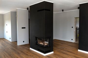 Wall Mural - A modern fireplace with a closed combustion chamber standing in the living room, painted black, with a washed corner pane.