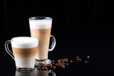 latte macchiato and cappuccino with glass cup and mug on a mirrored black background, space for text