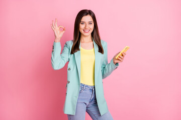 Wall Mural - photo of happy positive young woman hold hand phone message okay sign isolated on pastel pink color 