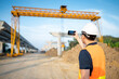 © zephyr_p - Smart Asian worker man or male civil engineer with protective safety helmet and reflective vest using using smartphone for taking photo at construction site.