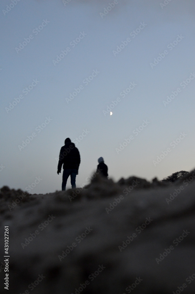 Ludzie o wschodzie księżyca na plaży - obrazy, fototapety, plakaty 