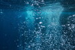 Air bubbles underwater in the ocean rising to surface, natural scene
