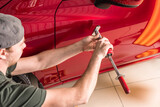 Fototapeta  - A specialist repairs a dent on a car body. PDR