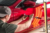 Fototapeta  - A specialist repairs a dent on a car body. PDR
