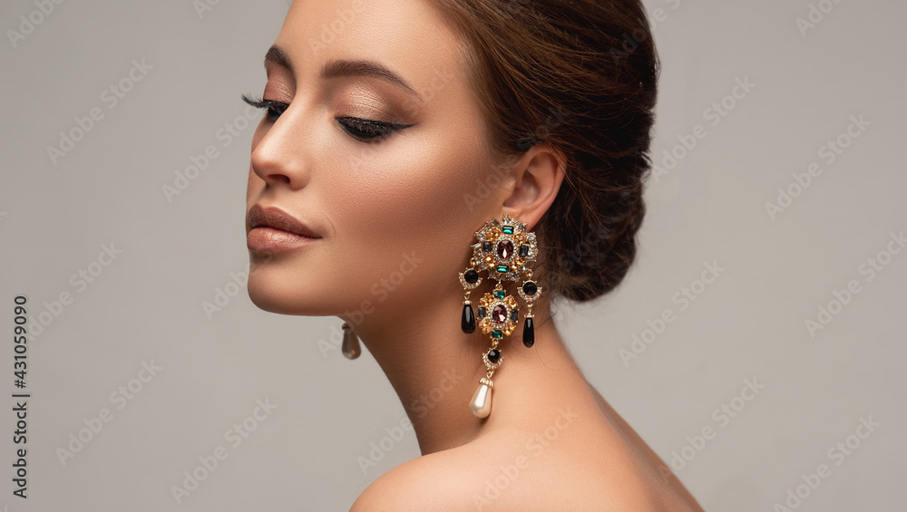 Beautiful woman with long big earrings. Beauty girl with elegant hairstyle and evening make-up. Makeup, cosmetics and jewelry - obrazy, fototapety, plakaty 