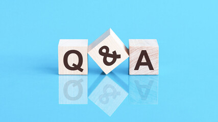 Poster - q and a word is made of wooden building blocks lying on the blue table, concept