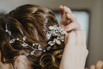 Bride fixing a beautiful hairpiece with teardrop crystal and flowers on the head