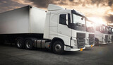 Fototapeta  - White Modern Semi Truck In A Row The Parking Lot At Sunset Sky.  Cargo Freight Truck Transportation.
