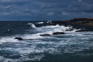 Wave in the ocean as water splashes on rocky shore on a stormy day in Qawra, Malta.