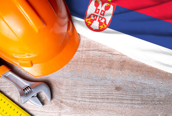 Serbia flag with different construction tools on wood background, with copy space for text. Happy Labor day concept.