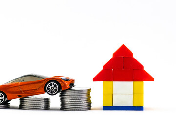 A blocks house toy, columns of coins and a toy car shot against white background in saving concept.