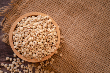 Wall Mural - Bowl of Adlay millet or pearl millet or Job's tears in wooden bowl on the sackcloth over wooden table background. copy space for text. Healthy food.