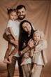 © Ananass - Portrait of a young family with two children in his arms photographed on a monochrome background
