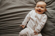 © Ananass - Beautiful cute baby lying and playing on the bed in the room, photo with daylight from the window