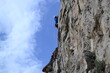 © Slava - A rock climber in a white helmet climbs a rock in sunny weather