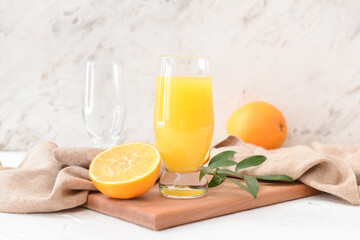 Glass with orange juice on light background