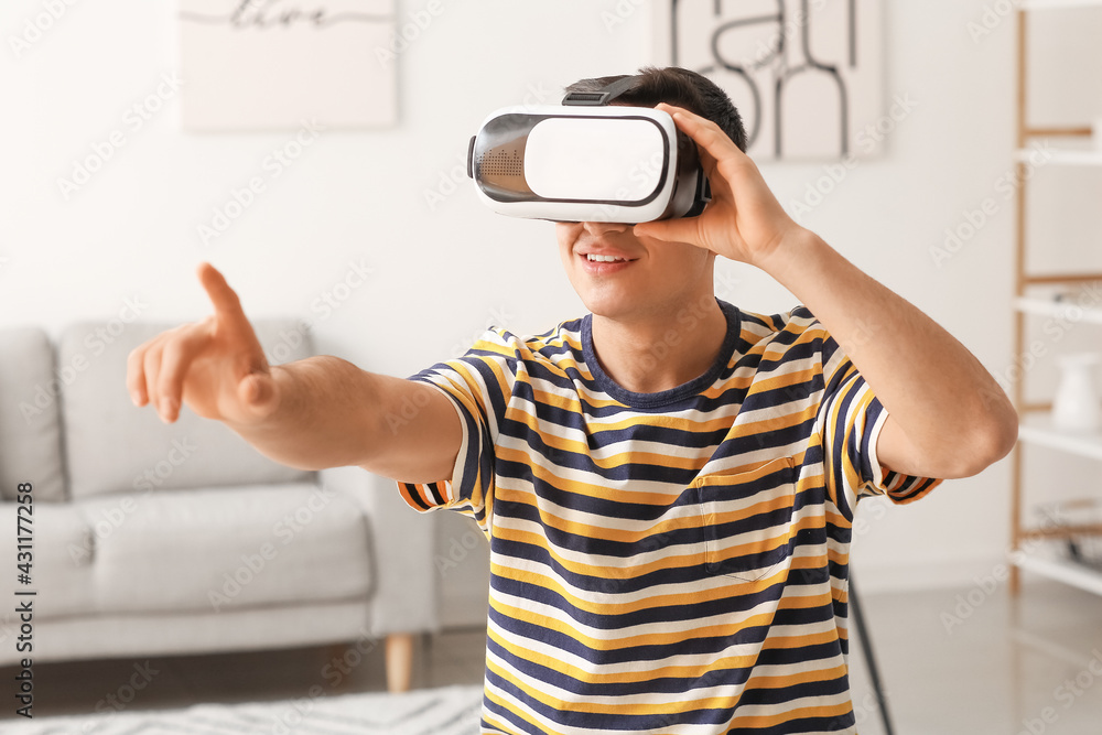 Young man with virtual reality glasses at home