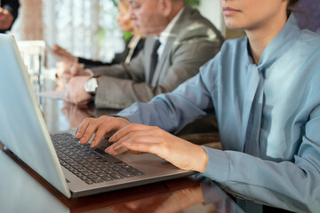 Poster - Young businesswoman working on a laptop against group of colleagues