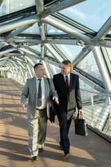 Wall Mural - Men in suits walking down aisle inside modern building and talking