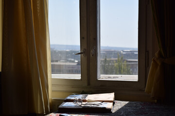 Eyeglass on an old photo album beside an apartment window - nostalgia concept