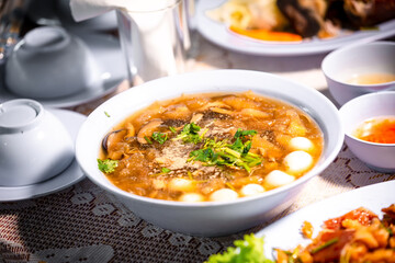 Chinese style soup or braised fish maw in red gravy with eggs, mushroom, and bamboo shoot in white bowl. Braised Fish Maw in Red Gravy with crab in bowl.