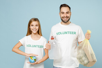 Two young couple teen girl man wears white t-shirt green title volunteer hold bag trash globe isolated on pastel blue color background. Voluntary free team work assistance help charity grace concept.