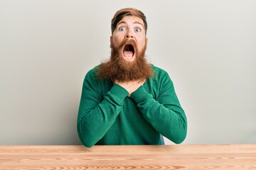 Poster - Young irish redhead man wearing casual clothes sitting on the table shouting and suffocate because painful strangle. health problem. asphyxiate and suicide concept.