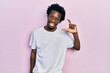 © Krakenimages.com - Young african american man wearing casual white t shirt smiling and confident gesturing with hand doing small size sign with fingers looking and the camera. measure concept.