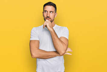 Poster - Handsome man with beard wearing casual white t shirt with hand on chin thinking about question, pensive expression. smiling with thoughtful face. doubt concept.