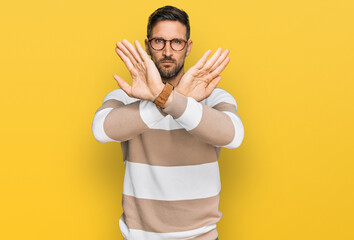 Wall Mural - Handsome man with beard wearing casual clothes and glasses rejection expression crossing arms doing negative sign, angry face