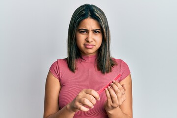 Wall Mural - Young latin woman using file nail clueless and confused expression. doubt concept.