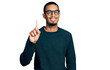 © Krakenimages.com - Young african american man wearing casual clothes and glasses showing and pointing up with finger number one while smiling confident and happy.