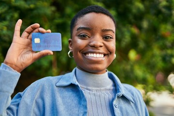 Wall Mural - Young african american woman smiling happy holding credit card at the city.