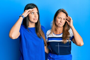 Canvas Print - Hispanic family of mother and daughter wearing casual clothes over blue background worried and stressed about a problem with hand on forehead, nervous and anxious for crisis