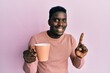 © Krakenimages.com - Handsome black man drinking a cup of coffee smiling with an idea or question pointing finger with happy face, number one
