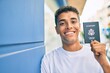 © Krakenimages.com - Young latin man smiling happy holding united states passport leaning on the wall at the city.