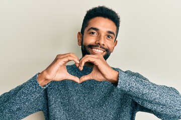 Wall Mural - Handsome hispanic man with beard wearing casual clothes smiling in love doing heart symbol shape with hands. romantic concept.