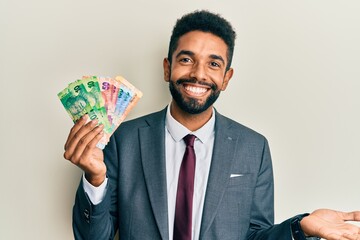 Poster - Handsome hispanic business man with beard holding south african rand banknotes celebrating achievement with happy smile and winner expression with raised hand