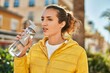 © Krakenimages.com - Young hispanic girl with relaxed expression drinking bottle of water at the city.