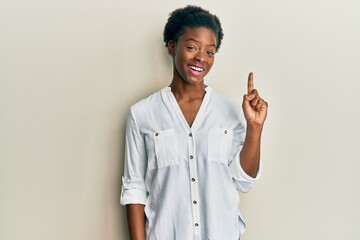 Poster - Young african american girl wearing casual clothes pointing finger up with successful idea. exited and happy. number one.