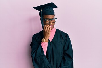 Poster - Young african american girl wearing graduation cap and ceremony robe looking stressed and nervous with hands on mouth biting nails. anxiety problem.