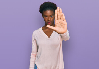 Sticker - Young african american girl wearing casual clothes doing stop sing with palm of the hand. warning expression with negative and serious gesture on the face.