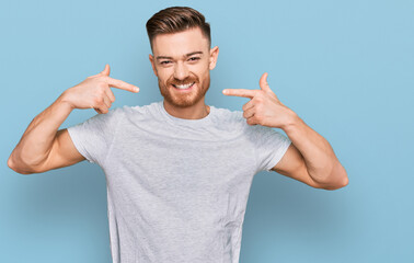 Young redhead man wearing casual grey t shirt smiling cheerful showing and pointing with fingers teeth and mouth. dental health concept.