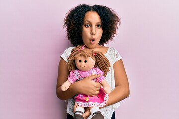 Sticker - Young little girl with afro hair holding animal doll toy scared and amazed with open mouth for surprise, disbelief face