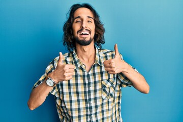 Young hispanic man wearing casual clothes success sign doing positive gesture with hand, thumbs up smiling and happy. cheerful expression and winner gesture.