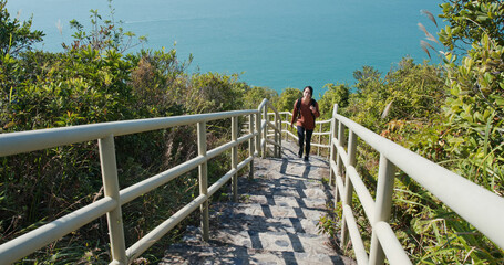 Poster - Woman hiking on steps from the sea background