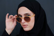 © .shock - Young muslim in traditional clothes or abaya and sunglasses posing in front of black chalkboard