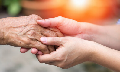 caregiver, carer hand holding elder hand in hospice care. philanthropy kindness to disabled concept.