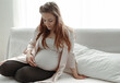 © puhimec - Stylish pregnant woman with a big belly sits on the couch at home.